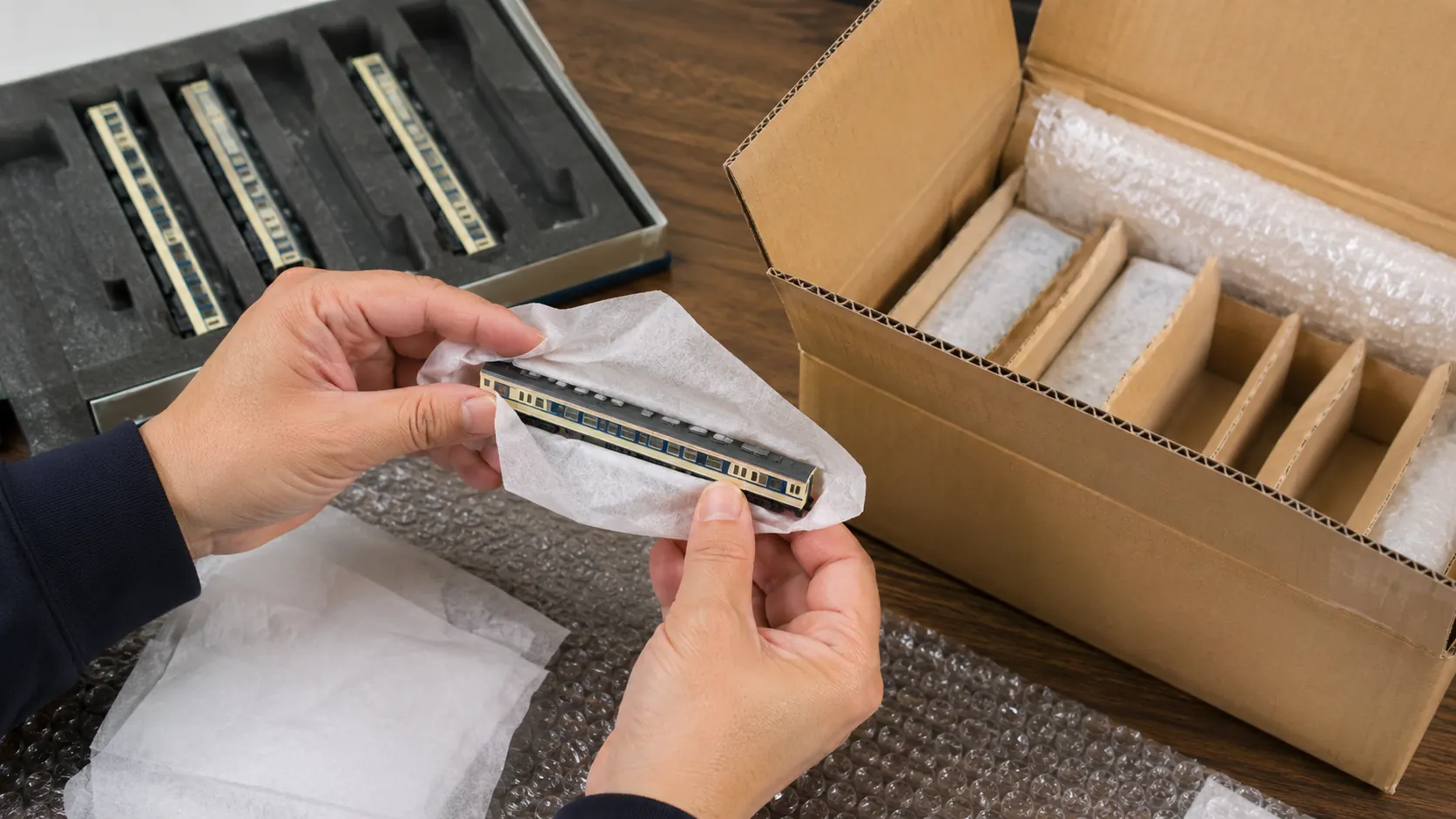 Hands carefully wrapping a Japanese N gauge model train car for international shipping